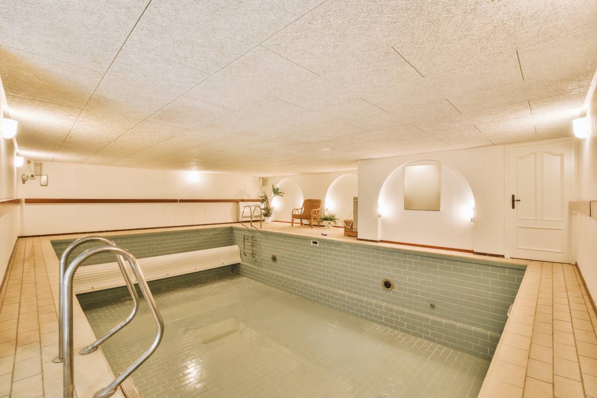 an indoor hot tub in the middle of a room with tile flooring and walls that have been painted white